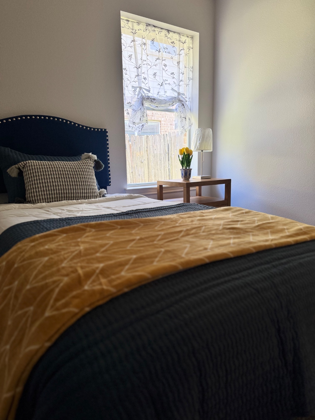 Private bedroom with navy headboard and warm gold bedding